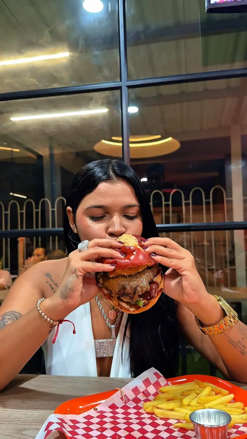 Clienta de Dakota mordiendo una burger en el local